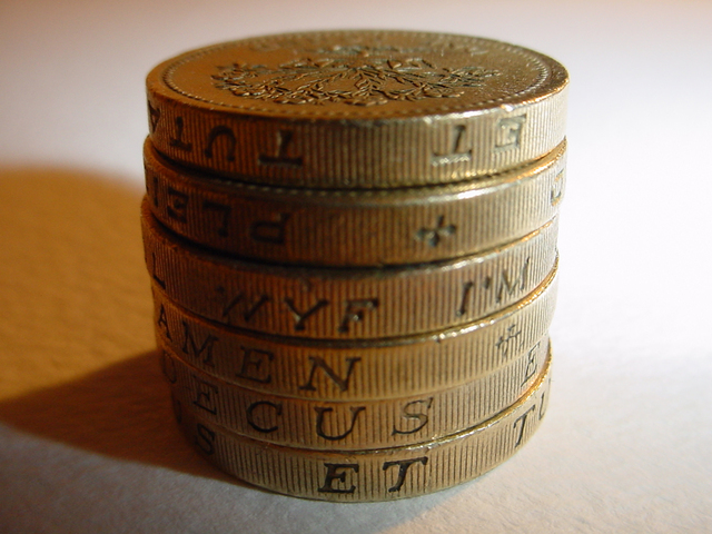kovové mince složené na sobě se stínem na stůl