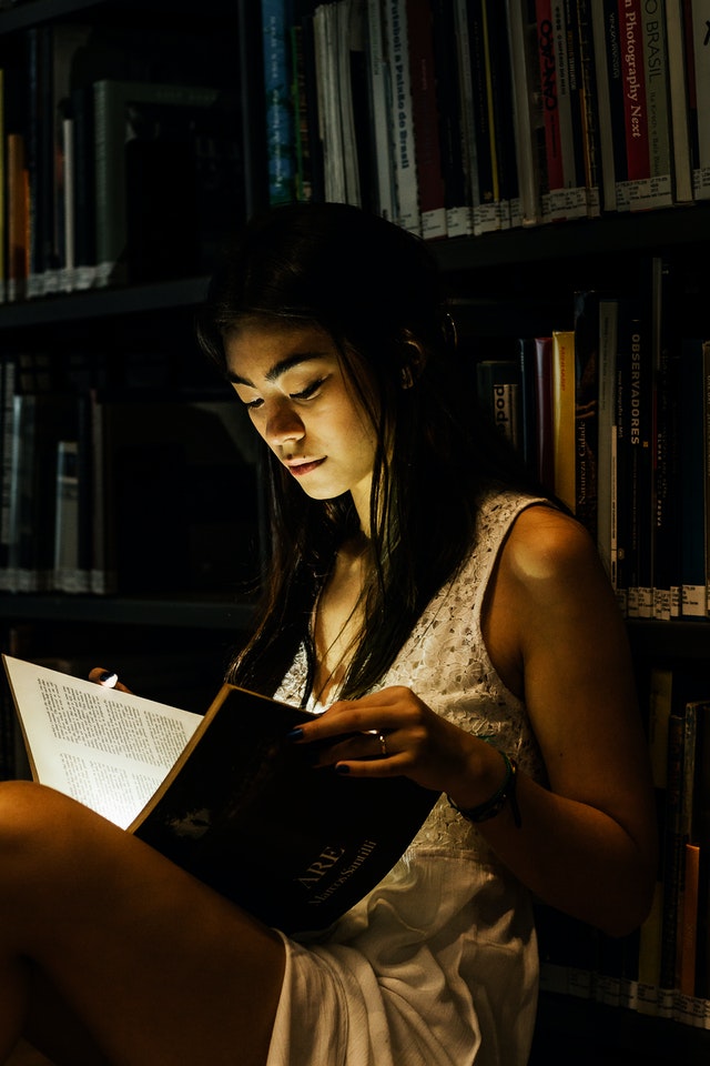 žena v osvětleném prostoru čte knihu